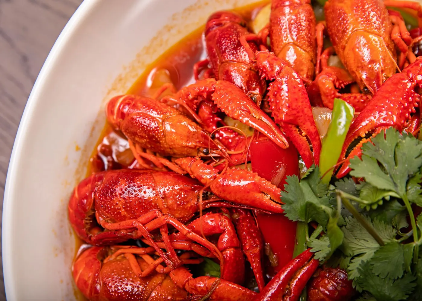 Bowl of bright red Cajun boiled crawfish with cilantro and chili